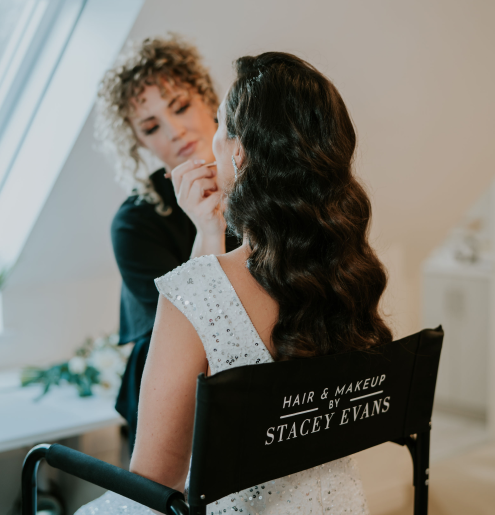 Action shot of Stacey Evans applying makeup to a bride sitting in a chair